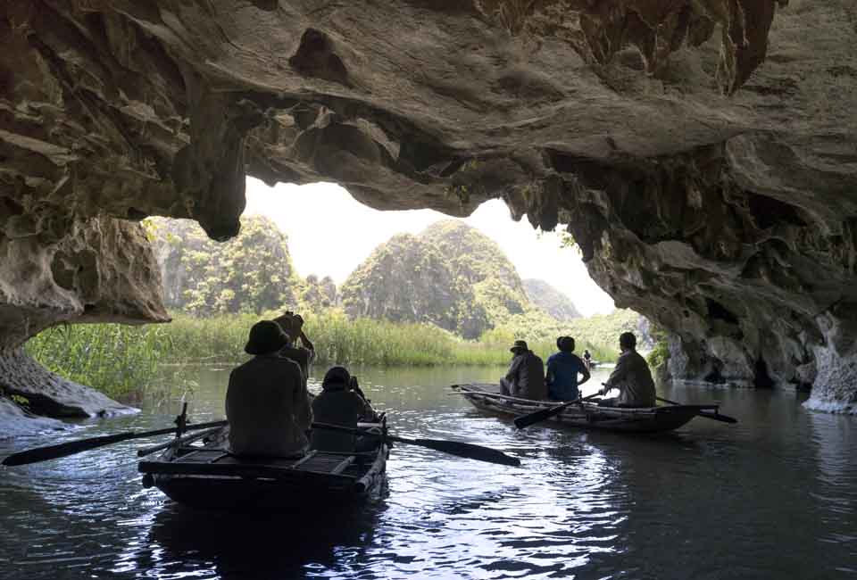 The tourists are traveling by boat into the cave in Ninh Binh Province The tourists are traveling by boat into the cave in Ninh Binh Province